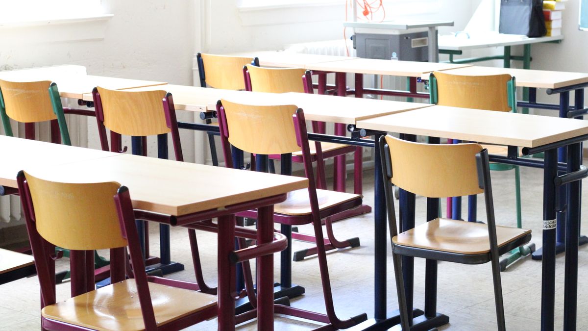 Rows of classroom tables with wooden chairs in an empty room