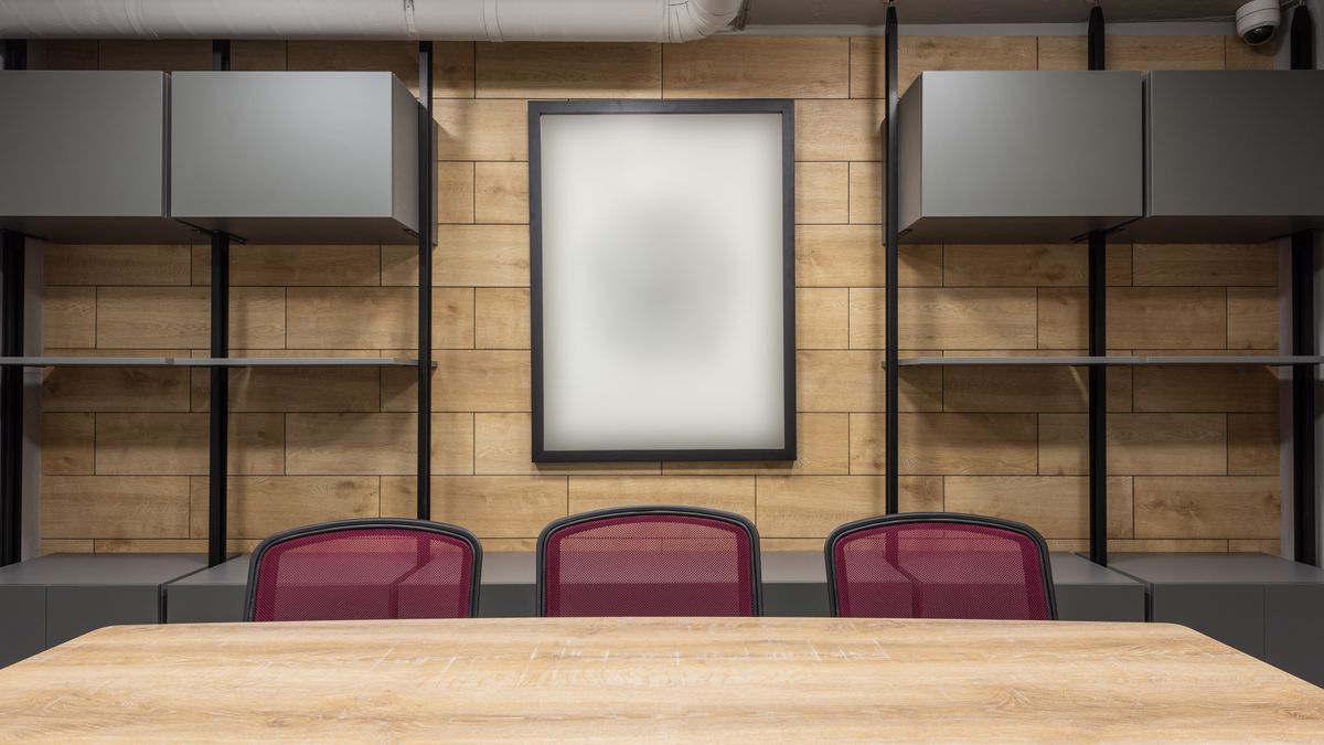 A meeting room with a long wooden table and eight mesh office chairs