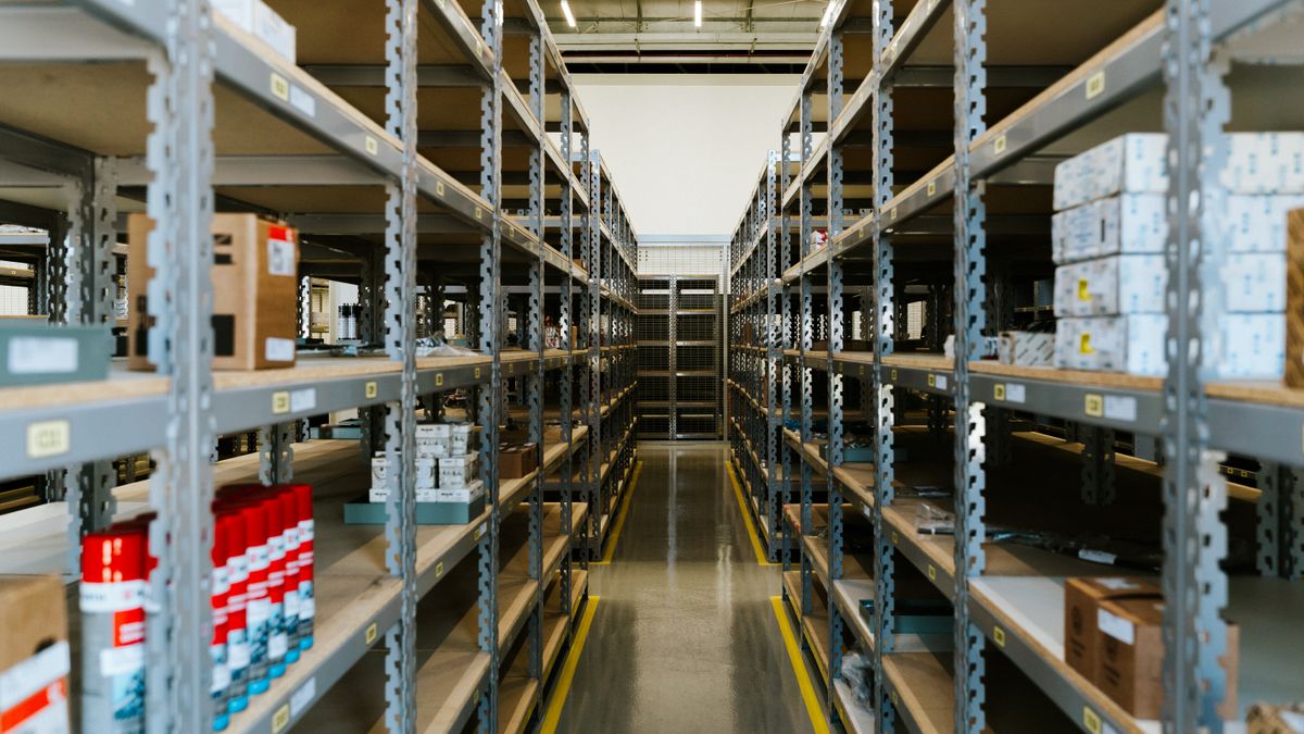 A clean, well-lit warehouse aisle stocked with boxed inventory
