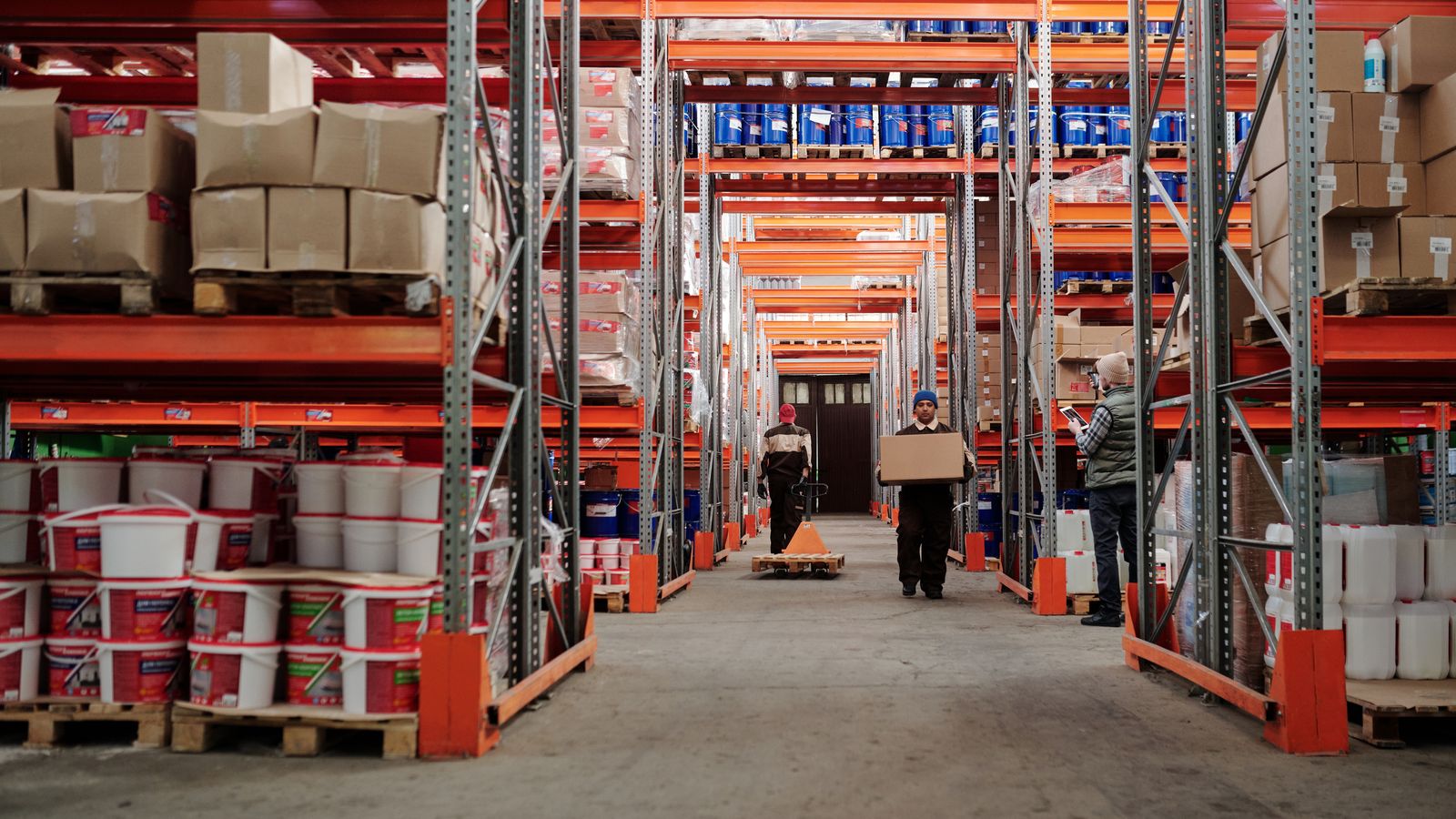 Warehouse workers moving boxed inventory between racked aisles