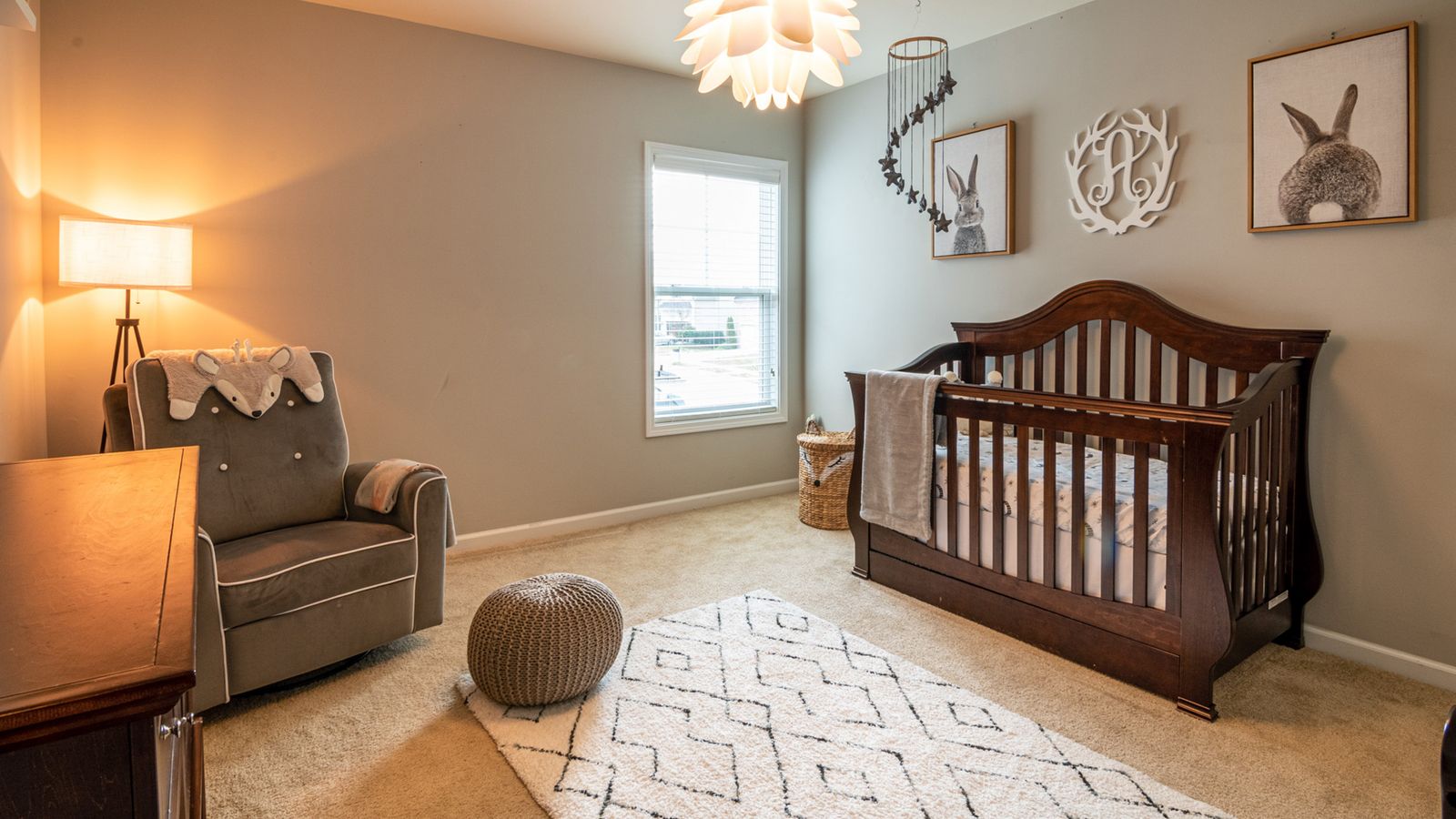 A nursery with a dark wood crib and a glider