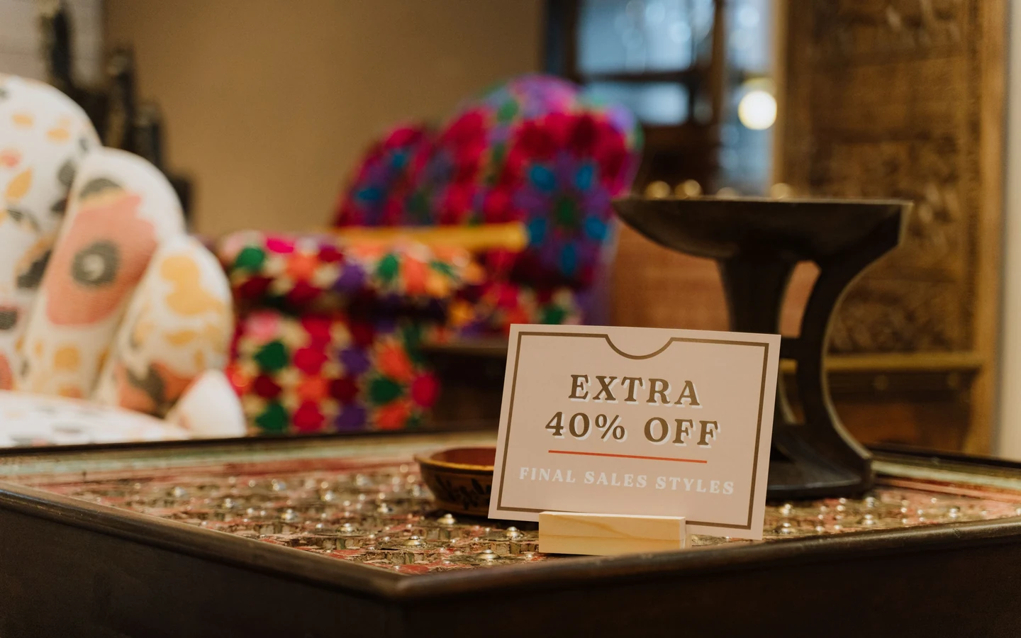 Extra 40% off final sales styles sign on a table among furniture and decor